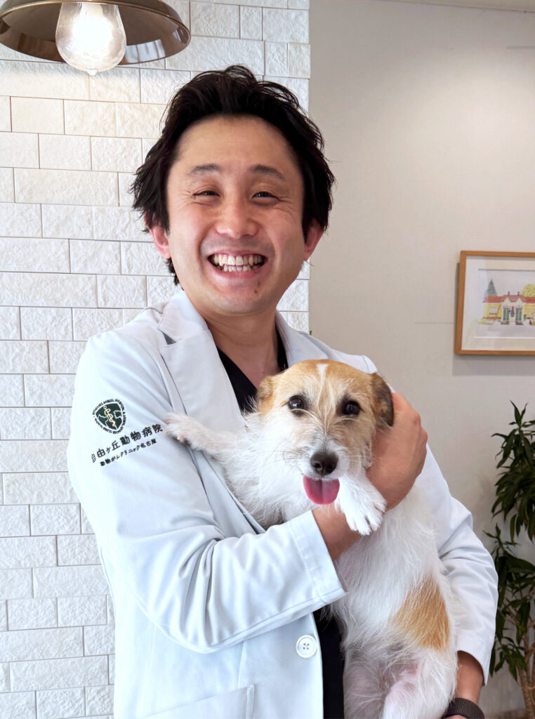 2026年院長近影、犬を抱いた笑顔の院長写真。